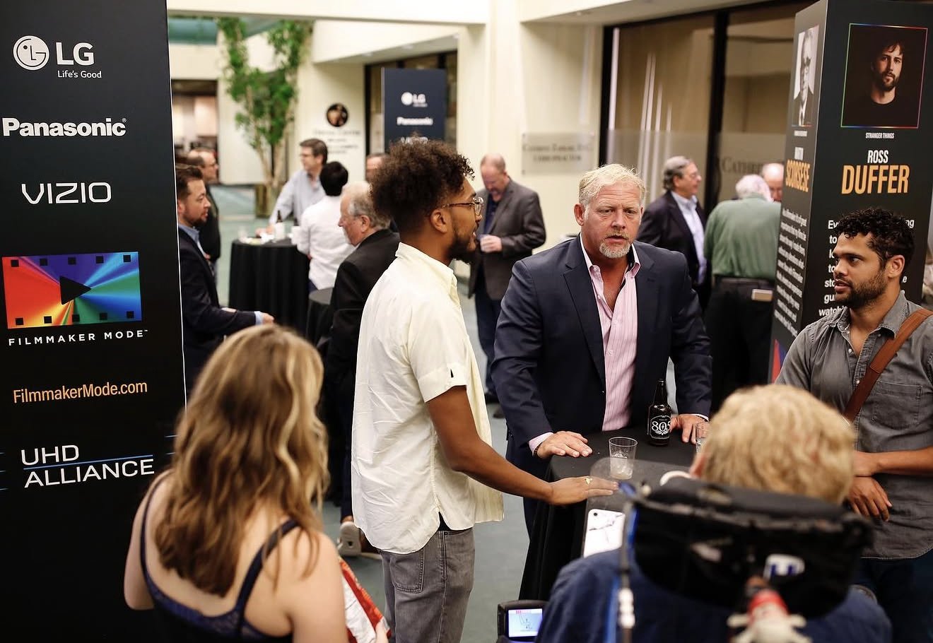Michael Hoog speaking with attendees at a Filmmaker Mode launch event, beside banners for LG, Panasonic, VIZIO, and the UHD Alliance